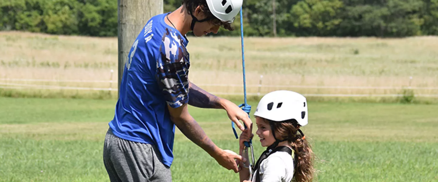 Staff helping camper with safety equipment