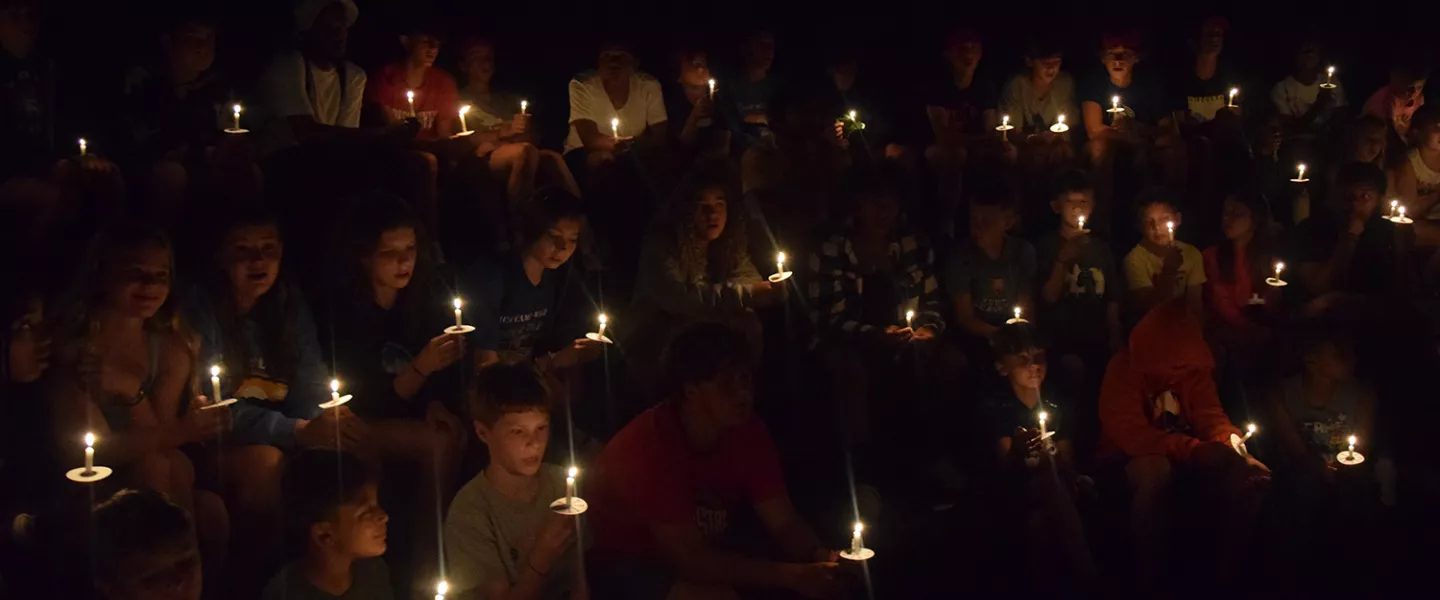 kids holding candles in the dark