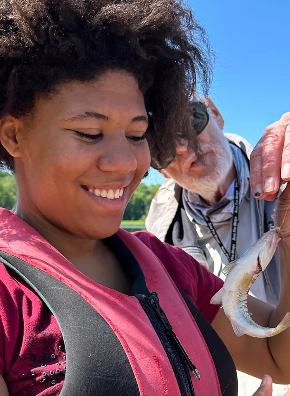 camper holding fish while staff helps