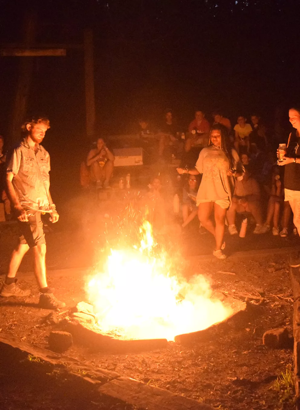 people around a roaring campfire