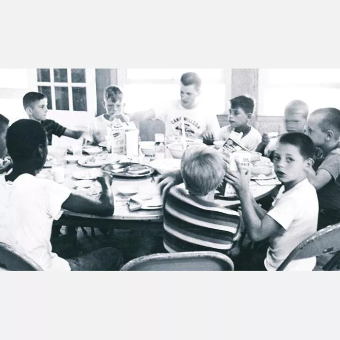 historical image of campers eating at a round table