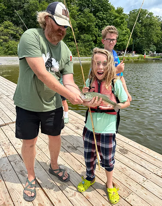 Staff and camper holding a fish