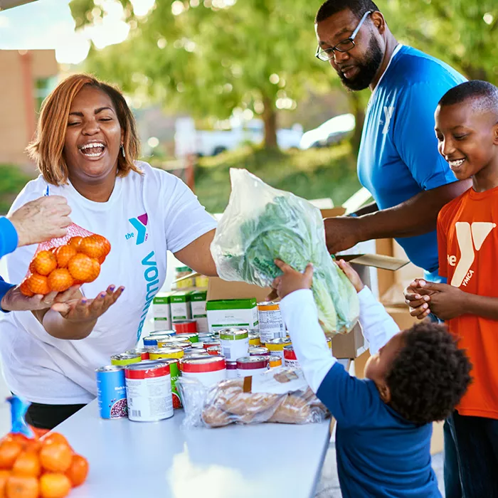 Volunteers with YMCA shirts sorting food and goods